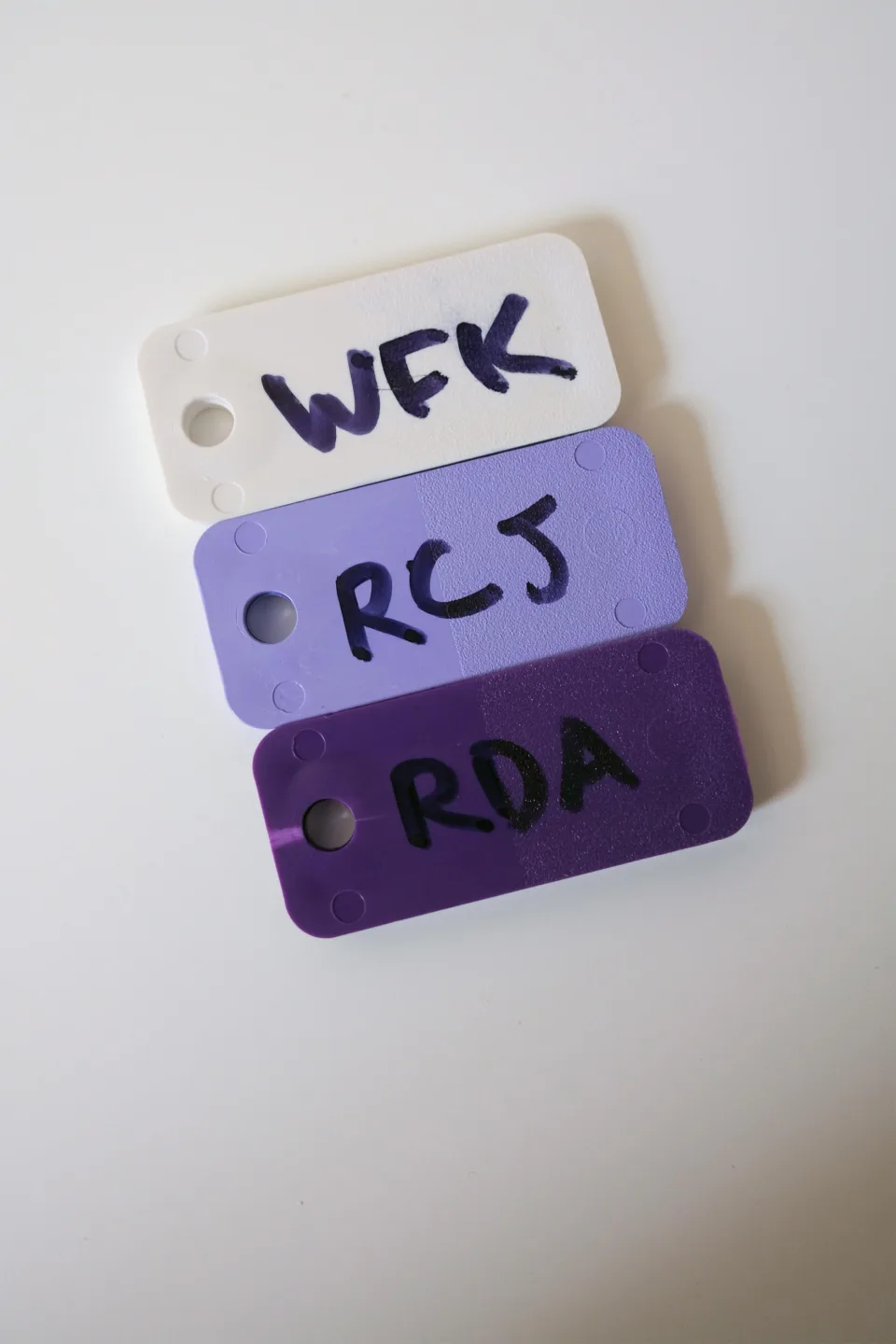 Three plastic color chips labeled WFK, RCJ, and RDA: white, lilac, and purple